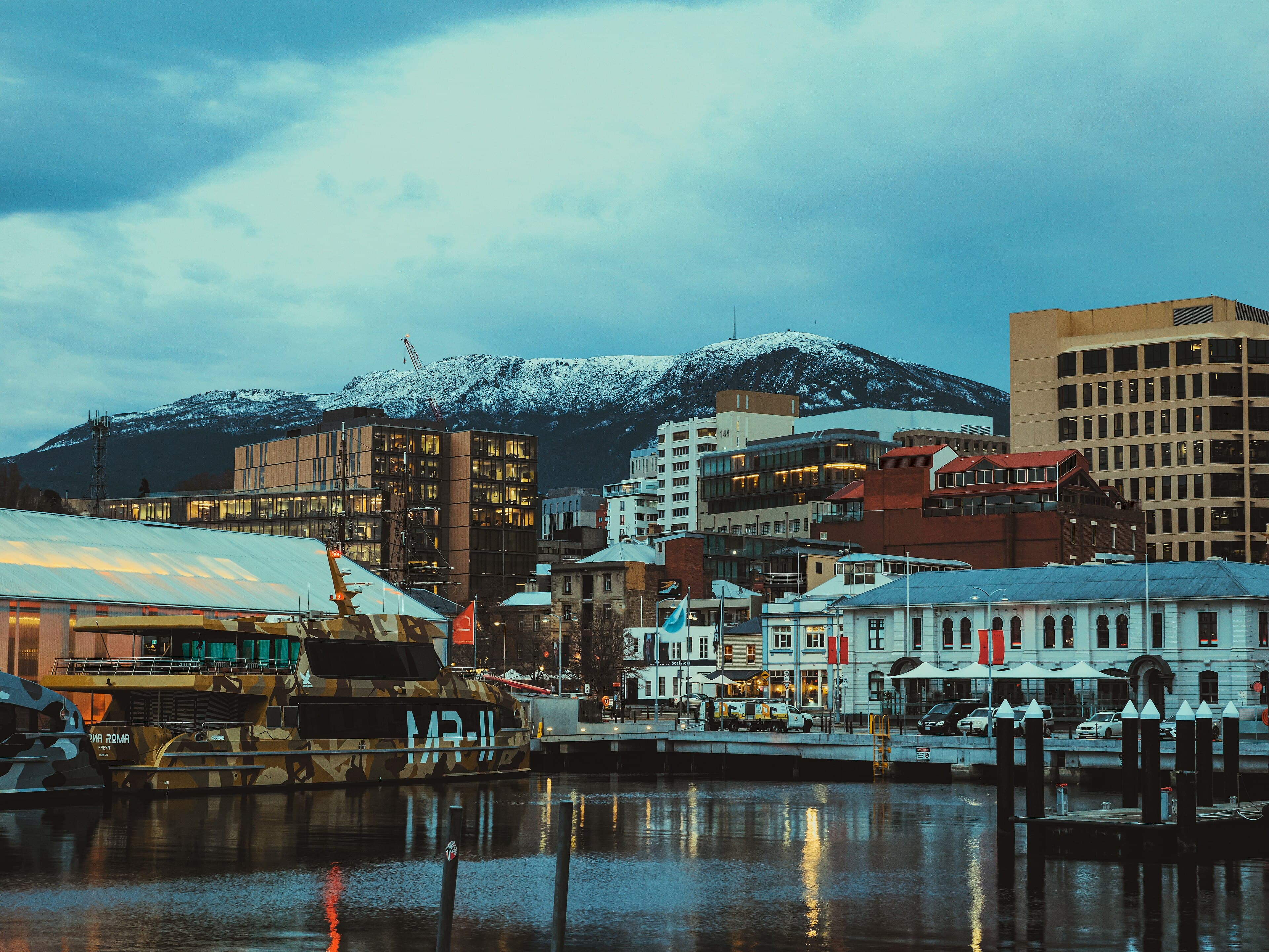 Hobart waterfront buildings and boats below snow-covered kunanyi